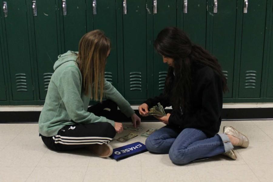 Kaitlyn Grieb and Blanca Blake count the funds raised by the selling of ayuda bands. The funds raised all go to supporting a Guatemalan childs education. 