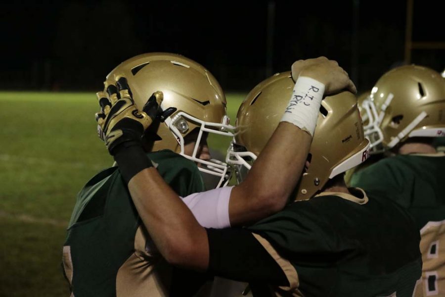 Teammates Bryce Coop (12) and Uriah Waters (12) embrace after a hard game. Coop is commemorating those he has lost with phrases like, I fight for those who cant. and others, as seen in this photo.