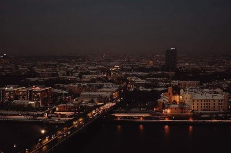 Latvia's capitol city of Riga is shown at night time. The relative dimness of the city's lights compared to a typical American city shows how traditional the country is, with mainly signs and lamp posts illuminating the city.