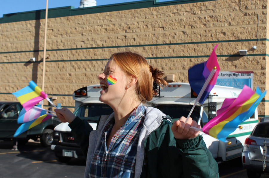 Abigail Kilpela (11) holds LGBTQ flags, dances and shows her kindness while welcoming students to school on Monday morning.