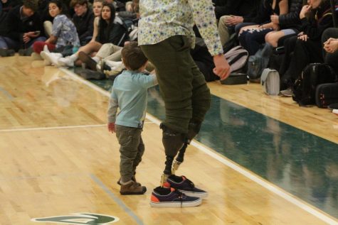 Mr. Noland walks hand in hand with his youngest son, Ben, after speaking during the assembly.