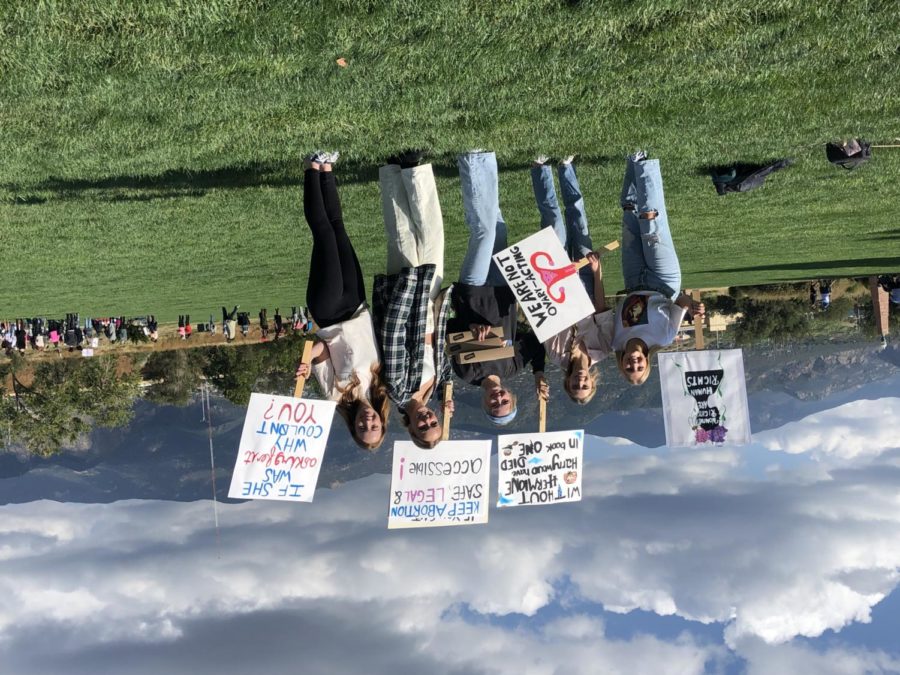 Manitou Springs High School students Claire Kisielnicki (12), Caylani Falbo (12), Adele Goodwin (12), Serena Holvenstot (12) and Addyson Sheffield (12) prepare for the Colorado Springs Womens March to begin in America the Beautiful Park on October 2, 2021. They brought donuts to give to protesters.