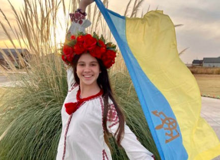 Sofiia Lobas (11) wears a traditional vishivanka and venok as she holds her home country of Ukraine’s flag. 