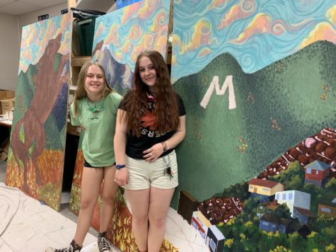 Lindsey Hinshaw (12) and Amelia Hamilton (12) stand in front of their Manitou mural.