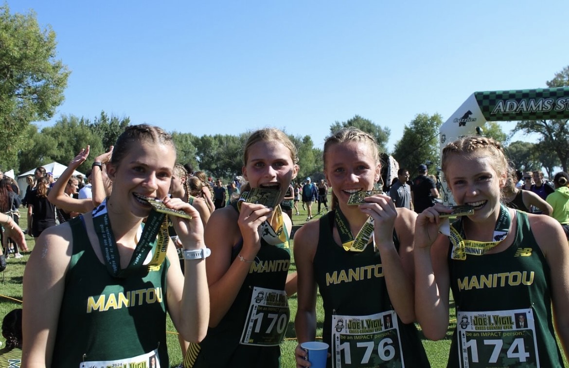 The girls cross country team biting down on medals post race.