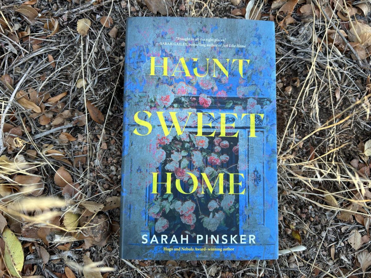 The book “Haunted Sweet Home” by Sarah Pinsker with rocks and plants in the background.