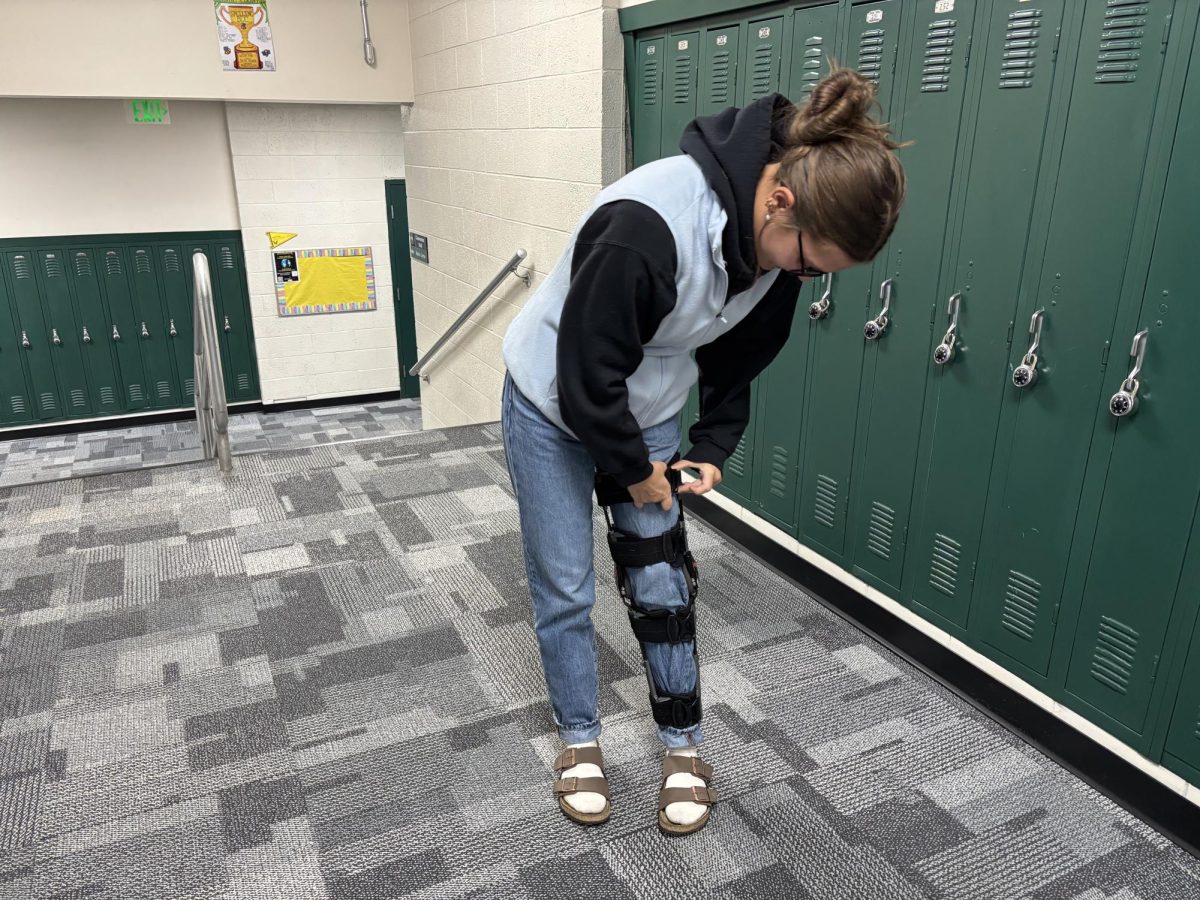 Nici Sharon adjusts her leg brace on Dec. 3 in the hallway. Nici Sharon has had multiple leg injuries in the past during her soccer career, and believes that she will make a full recovery for the girls soccer season.