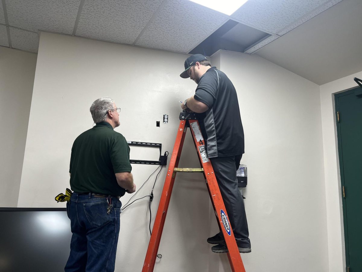 Randy Woofter and Trevor Paskavich install the first of two touch screens throughout MSHS on Oct. 16, 2024, with a goal of freeing up space in trophy cases around the school. These screens were designed to hold digital versions of composite photos, awards, and other memorabilia.