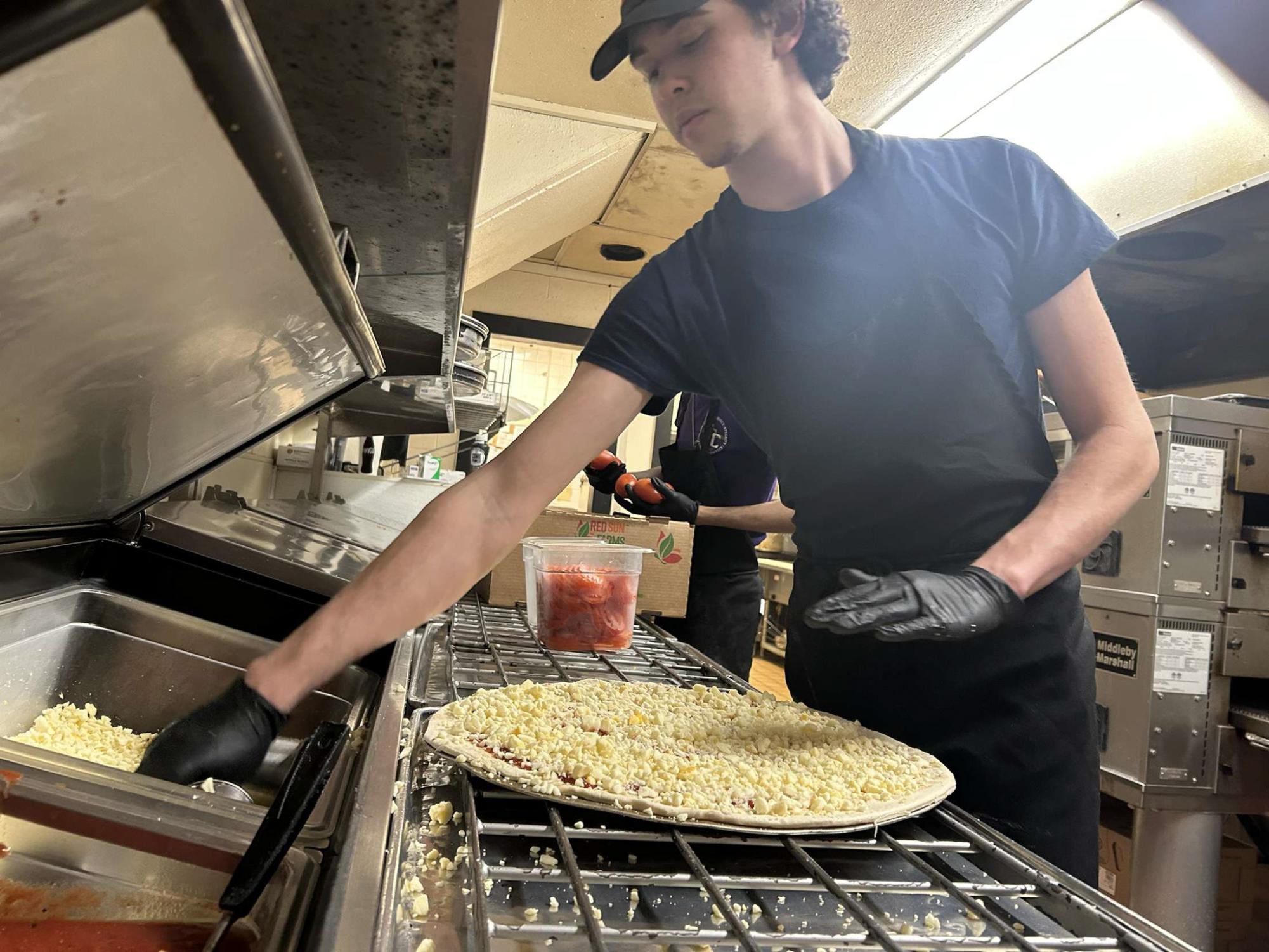 Student Landon Foster (12) makes a pizza for his job at Savelli's.