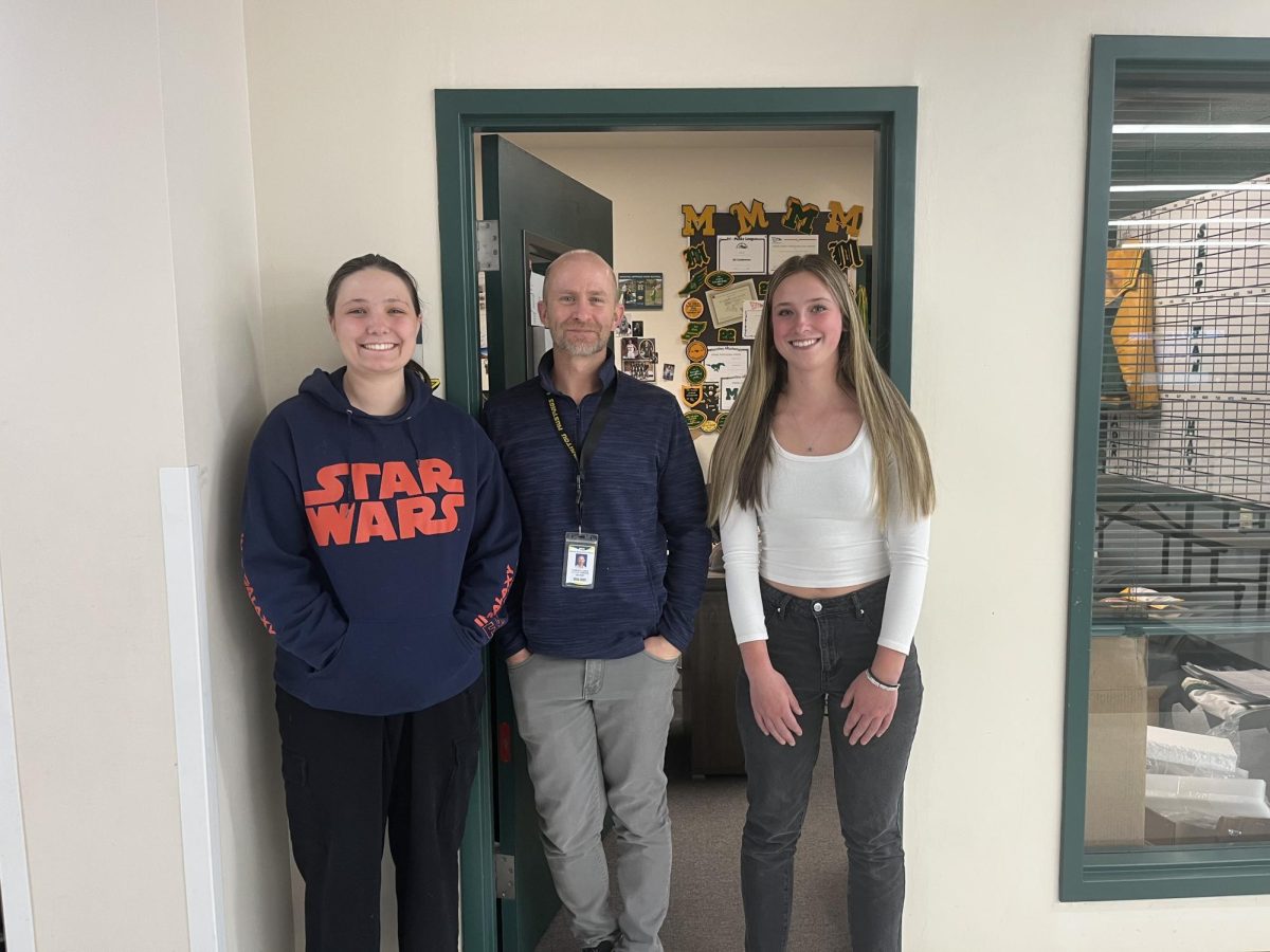 Girls' golf players Madi Sharon (12) and Addie Dorsey (10) stand in the doorway alongside Cameron Jones, the Athletic Director at MSHS.