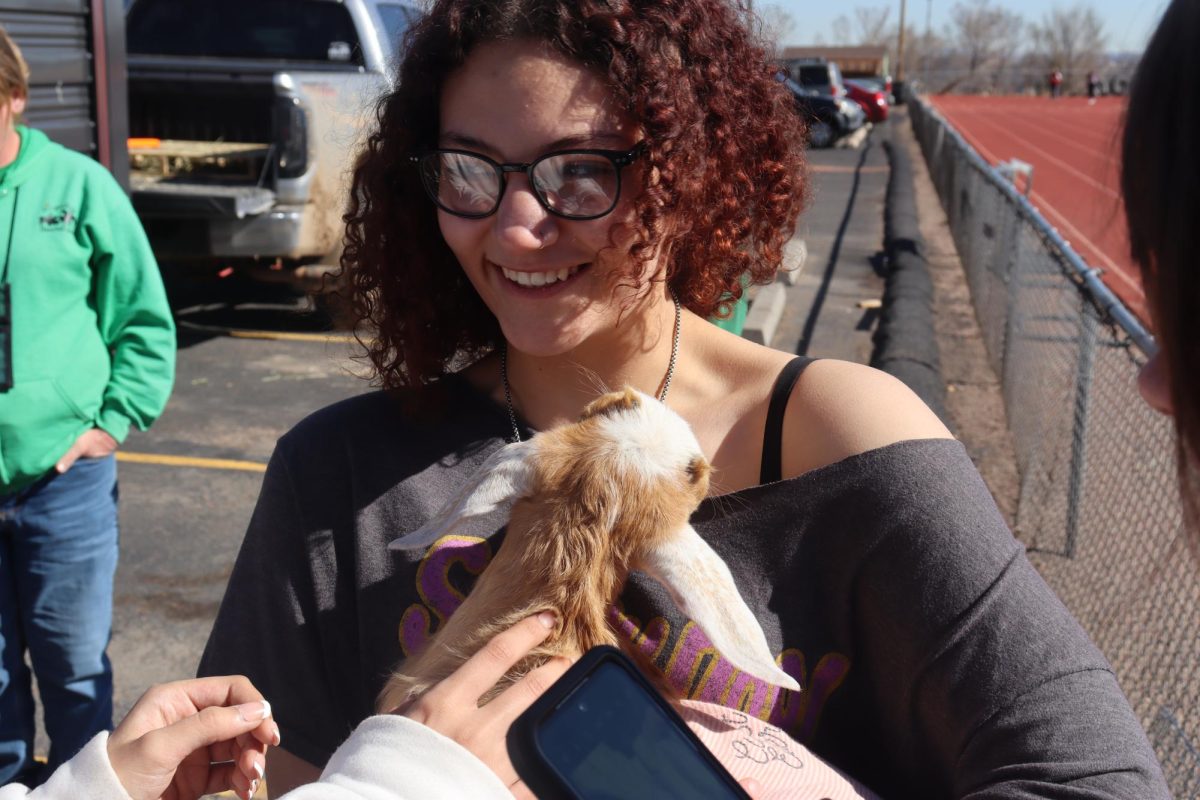 During session one of Mustang Strong Day on Mar.5, Morgan Shlutz (12) holds a baby goat at the petting zoo on the track.