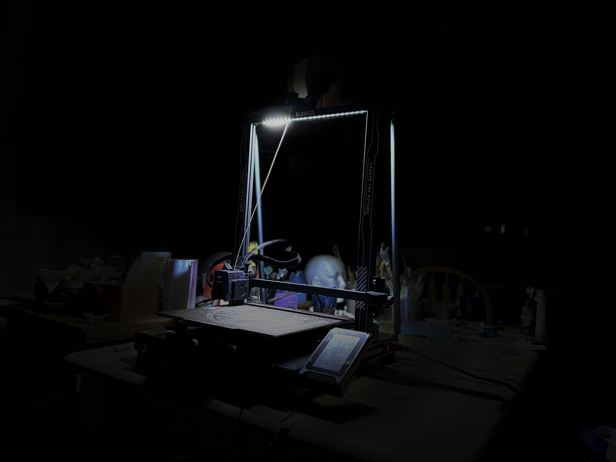 A 3D printer in the dark lit up by the display light.