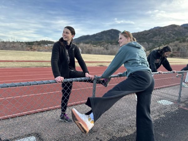 Violet Reddinger (9) and Chloe Bresnahan (10) warm up on the fence at the first Track and Field practice on Feb. 23.